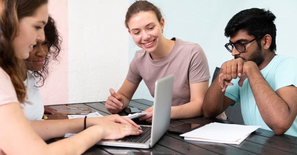 a group of people sitting at a table looking at a laptop