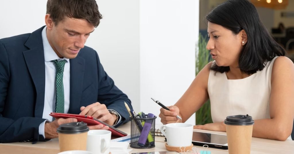 a man and woman sitting at a table looking at a tablet