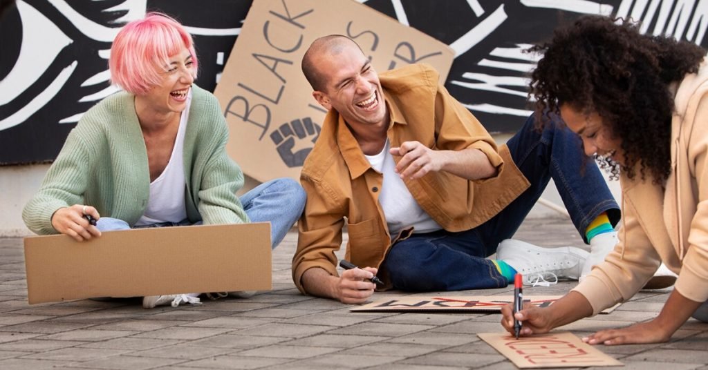 a group of people sitting on the ground and making sign boards