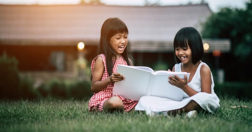 two girls sitting on the ground and reading books