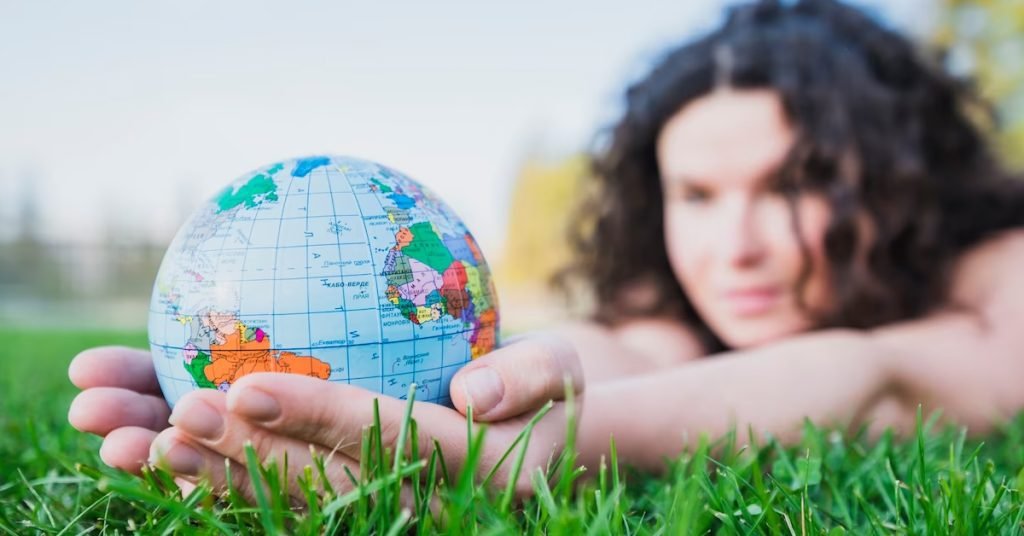 a woman lying on grass holding a globe