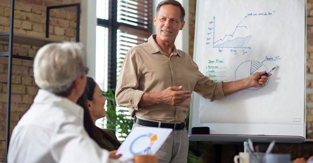 a man standing in front of a whiteboard and explaining the graphs