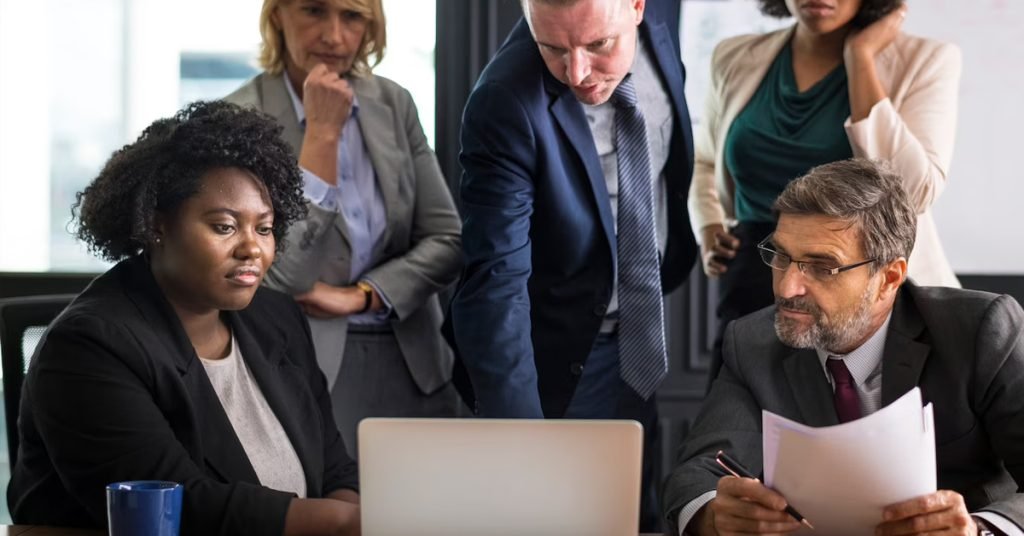 a group of people in suits looking at a laptop