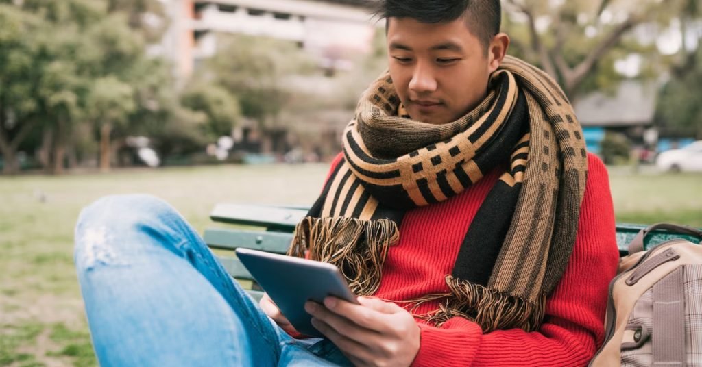 a man sitting on a bench looking at a tablet