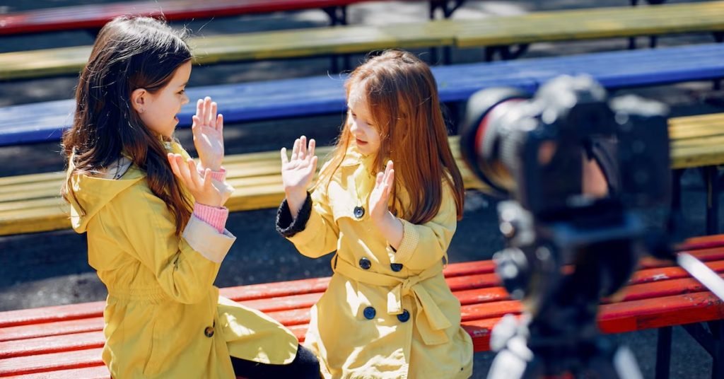 two girls in yellow coats clapping and giving high five infront of a camera