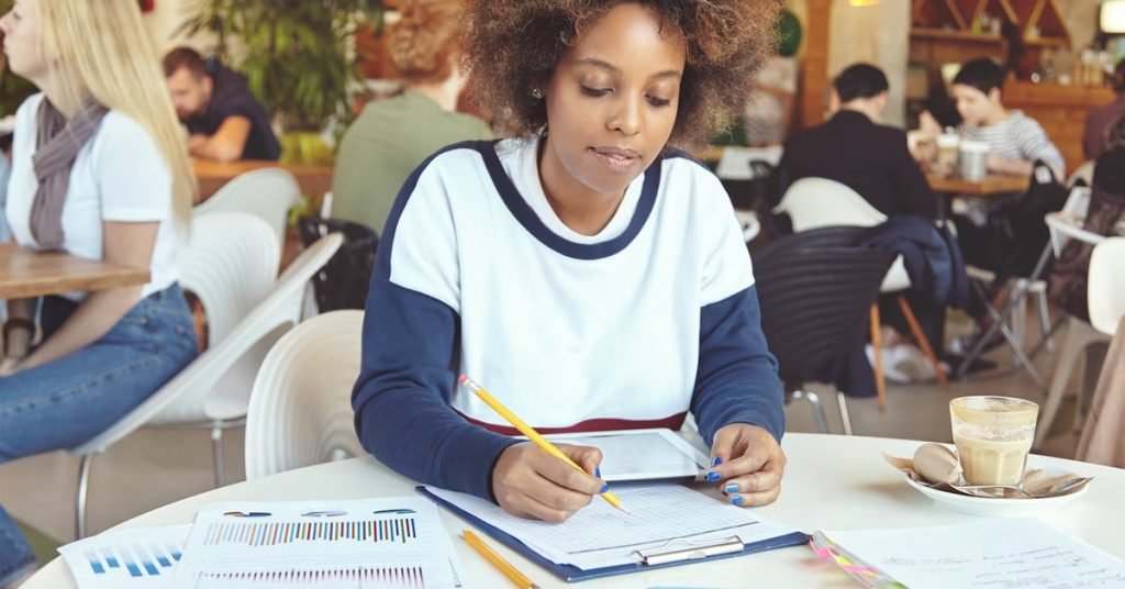 a woman sitting at a table writing on a clipboard