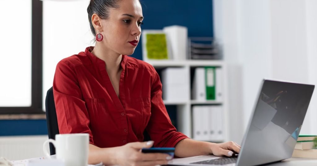 a woman in a red shirt using a laptop