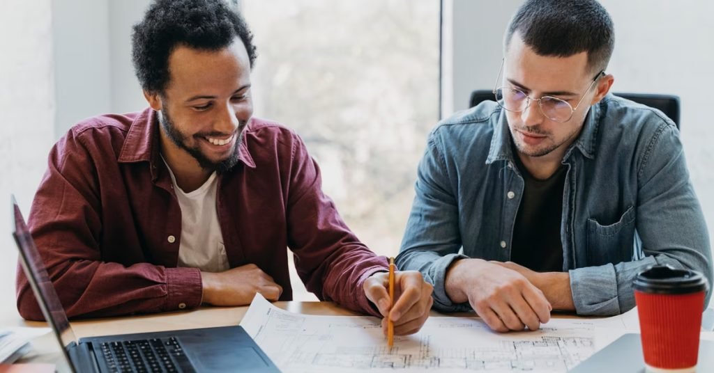 a couple of men looking at a blueprint