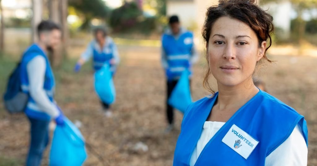 a woman in blue jackets with a group of people in the background cleaning garbage