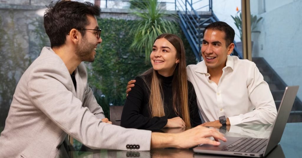 a group of people sitting at a table looking at a laptop