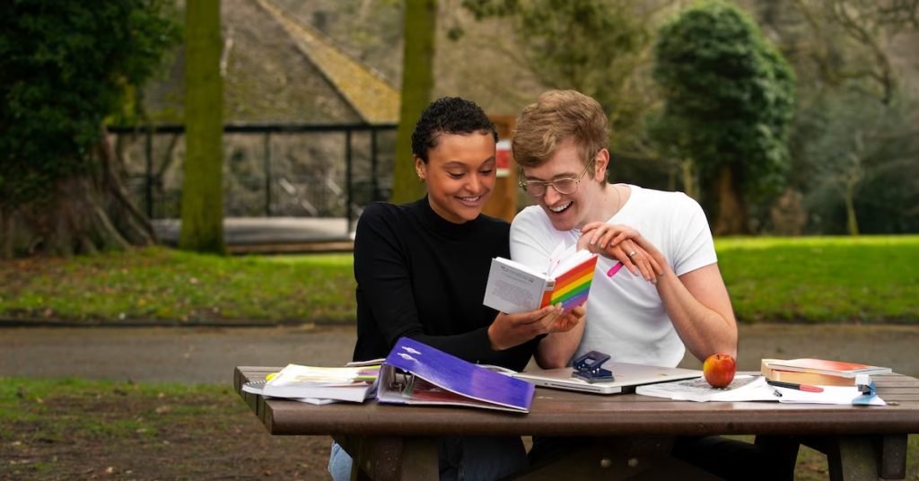 a man and woman reading a book at a picnic table