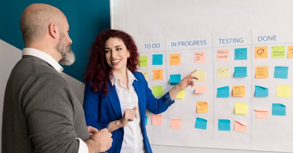 a man and woman standing next to a whiteboard with sticky notes