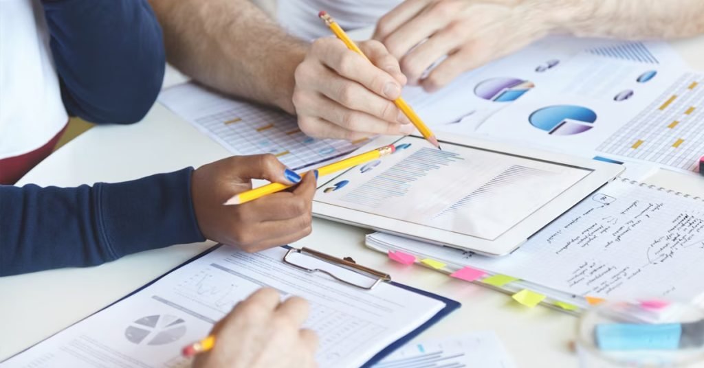 a group of people holding pencils and pointing towards graphs