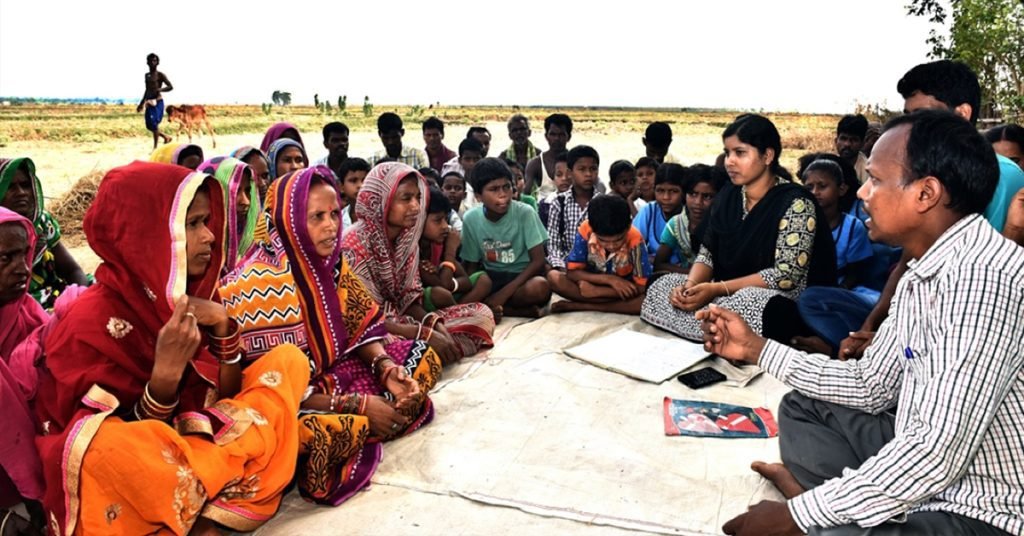 a group of people sitting on the ground in a village