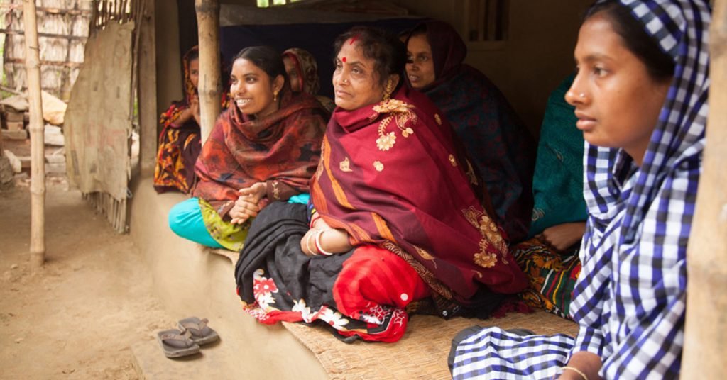 a group of local women sitting on ground