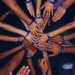 a group of hands with blue bracelets